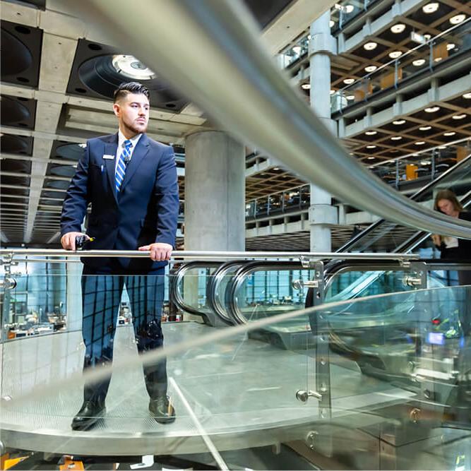 A male security guard in a suit looking over a rail in an office environment